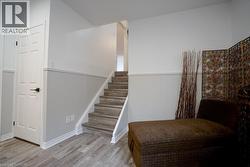 Staircase featuring wood-finish treads and risers, white stringers, and a prominent wainscoting detail - 