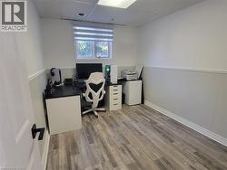 Room featuring a window with privacy blinds, wood-finish flooring, white paneling, and an acoustic tile ceiling - 