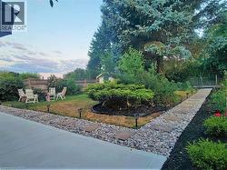 Expansive backyard featuring a concrete patio, a winding stone path with stepping stones, and mature trees - 