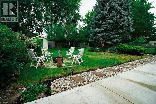 Expansive backyard featuring a large lawn, mature trees, a stepping stone pathway, and a detached storage shed - 147 Muriel Crescent, London, ON 