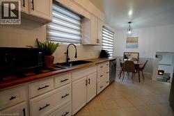 Kitchen featuring white cabinetry, wood-finish countertops, and a black sink with a matching faucet - 