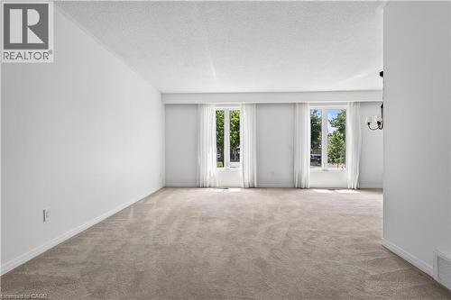 Spacious Living Room featuring light-colored carpeting, white walls, and bright white trim - 5051 Brady Avenue, Burlington, ON 