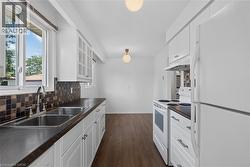Eat-in Kitchen featuring a double basin stainless steel sink, white cabinetry with clear glass upper doors - 