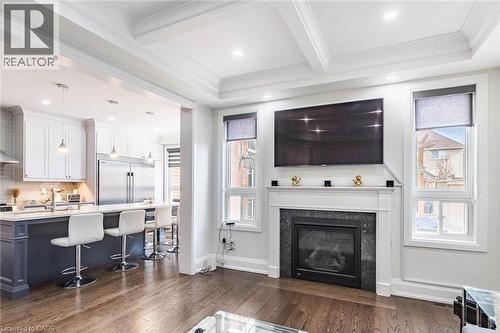 Living space featuring a fireplace with a dark stone surround and white mantel, hard surface flooring, recessed lighting, and a coffered ceiling - 47 Hawke Crescent, New Tecumseth, ON 