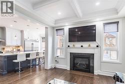 Living space featuring a fireplace with a dark stone surround and white mantel, hard surface flooring, recessed lighting, and a coffered ceiling - 