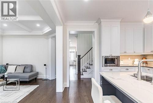 Modern kitchen featuring white cabinetry, a built-in microwave, and a large island with a light-toned countertop and integrated sink - 47 Hawke Crescent, New Tecumseth, ON 
