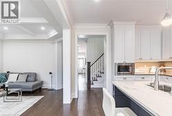 Modern kitchen featuring white cabinetry, a built-in microwave, and a large island with a light-toned countertop and integrated sink - 