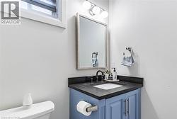 Bathroom vanity with blue cabinetry, a dark countertop, and an undermount sink - 