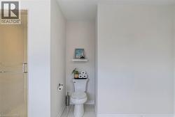 Toilet alcove featuring white walls and a white floor tile - 