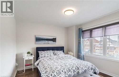 Bright bedroom with white walls, dark wood-finish flooring, and a large window featuring roller shades - 47 Hawke Crescent, New Tecumseth, ON 