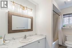 Bathroom featuring a single vanity with an oval sink, a framed mirror, and a four-light vanity fixture - 