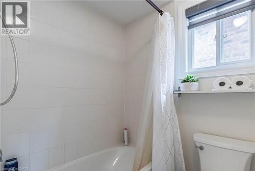 White tiled shower-tub combination featuring a window with a roller shade - 47 Hawke Crescent, New Tecumseth, ON 