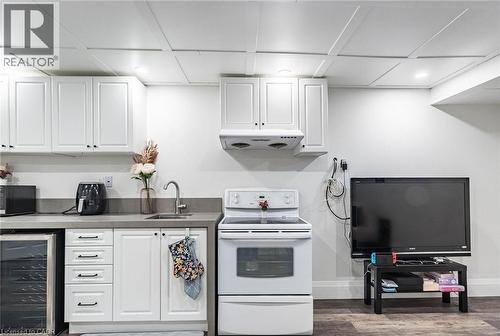 Compact kitchen area featuring white cabinetry, a stainless steel sink, a smooth-top electric range, and a beverage cooler - 47 Hawke Crescent, New Tecumseth, ON 