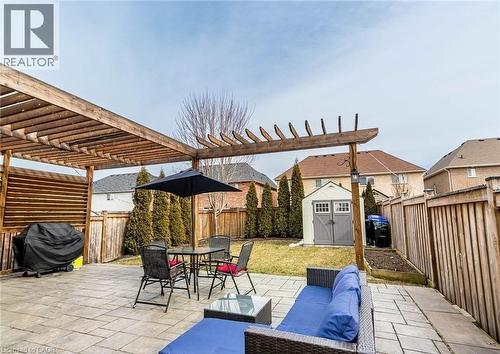 Spacious outdoor patio area featuring a stone paver surface, a wooden pergola structure, and a dedicated storage shed - 47 Hawke Crescent, New Tecumseth, ON 
