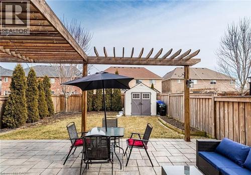 Expansive backyard featuring a stone paver patio, a wooden pergola structure, a manicured lawn, a privacy fence, and a storage shed - 47 Hawke Crescent, New Tecumseth, ON 