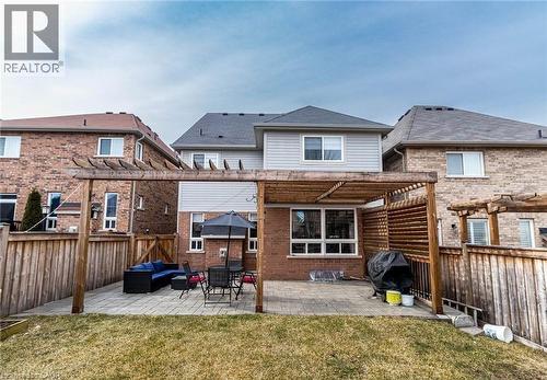 Expansive backyard featuring a stone paver patio, a wooden pergola structure, privacy fencing, and a partial grass lawn - 47 Hawke Crescent, New Tecumseth, ON 