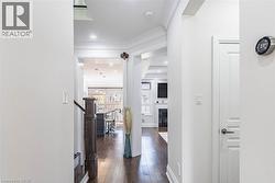 Hallway featuring wood-finish flooring, white paneled doors, recessed lighting, and crown molding - 