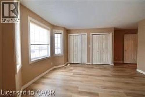 Spacious room featuring light wood-finish flooring, neutral wall tones, and white baseboards - 17 Hawkswood Drive, Kitchener, ON 