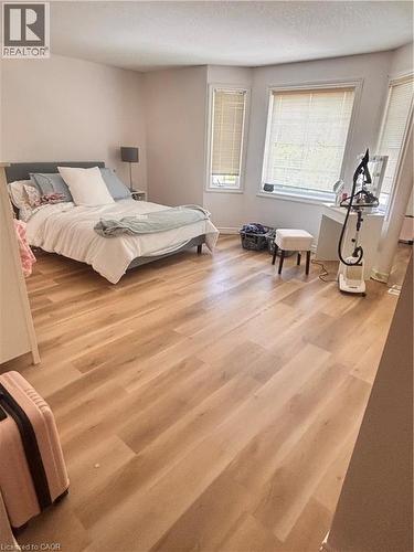 Spacious room featuring light wood-finish flooring, light-toned walls, and multiple windows with blinds - 17 Hawkswood Drive, Kitchener, ON 