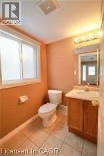 Bathroom featuring a vanity with wood-finish cabinetry, a single basin sink, and an overhead light fixture - 17 Hawkswood Drive, Kitchener, ON 
