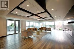 Spacious common area featuring wood-finish flooring, a wall of expansive windows, recessed lighting, and direct access to an outdoor patio - 