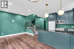 Kitchen with dark teal cabinetry, granite countertops, and stainless steel appliances - 