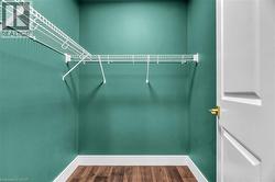 Walk-in closet featuring vibrant green walls, white wire shelving, wood-finish flooring, and white baseboards - 