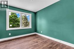 Room featuring a large window, wood-finish flooring, white baseboards, and a recessed ceiling light - 
