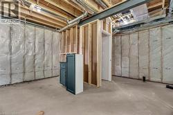 Unfinished basement offering flexible potential, featuring concrete flooring, exposed wood framing, insulation-ready walls, visible HVAC ductwork, and a partial doorway opening - 