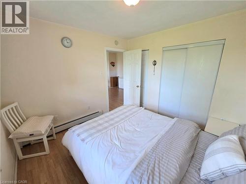Bedroom featuring wood-finish flooring, light-toned walls, and a ceiling light fixture - 2373 E King Street E Unit# 37, Hamilton, ON 