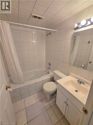 Bathroom featuring a jetted tub, ceramic tile surround and flooring, white vanity with integrated sink, and chrome fixtures - 2373 E King Street E Unit# 37, Hamilton, ON 