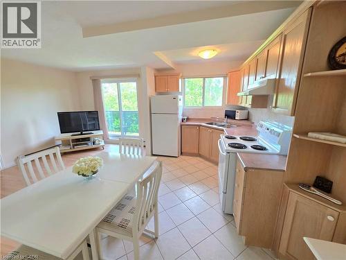 Open-concept living space featuring a kitchen with wood-finish cabinetry, white appliances, and a tiled floor - 2373 E King Street E Unit# 37, Hamilton, ON 