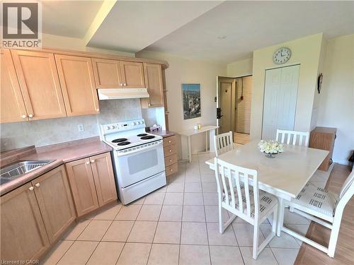 Kitchen and dining area featuring light wood-finish cabinetry, a white electric range, and a tile backsplash - 2373 E King Street E Unit# 37, Hamilton, ON 
