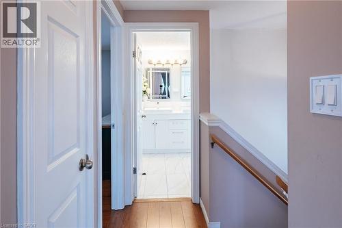 Hallway featuring wood-finish flooring, light tan wall color, white trim, and a wood handrail - 171 Mcnichol Drive, Cambridge, ON 