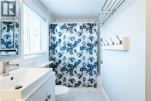 Bathroom featuring a built-in tub with tile surround, white vanity with integrated sink, chrome faucet, and a wall-mounted mirror - 171 Mcnichol Drive, Cambridge, ON 