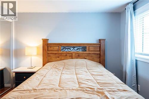 Bedroom featuring a wood-finish headboard with decorative metalwork, light blue wall paint, and a window with blinds and drapes - 171 Mcnichol Drive, Cambridge, ON 