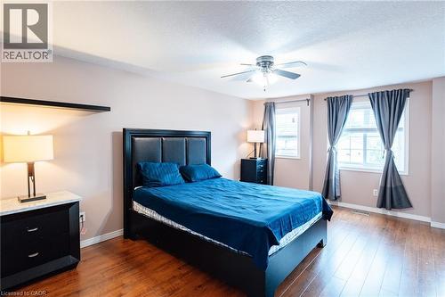 Spacious room featuring rich wood-finish flooring, a ceiling fan with integrated lighting, and multiple windows - 171 Mcnichol Drive, Cambridge, ON 