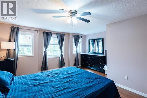 Interior room featuring wood-finish flooring, multiple windows with blinds, a ceiling fan with integrated lighting, and neutral-toned wall paint - 171 Mcnichol Drive, Cambridge, ON 
