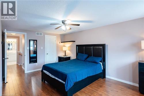 Bedroom featuring wood-finish flooring, a ceiling fan with integrated lighting, and a white interior door - 171 Mcnichol Drive, Cambridge, ON 