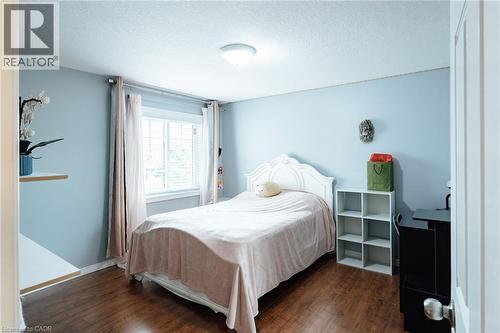 Bedroom featuring wood-finish flooring, a window with horizontal blinds, and a flush-mount ceiling light - 171 Mcnichol Drive, Cambridge, ON 