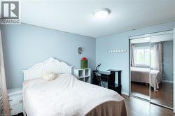 Bedroom featuring wood-finish flooring, light blue walls, a window with natural light, and a built-in mirrored closet - 