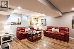Spacious open-concept living area featuring wood-finish flooring, recessed lighting, and light gray wall paint - 