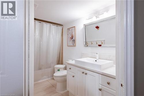 Bathroom featuring a white rectangular vessel sink, white vanity with cabinet storage, and a built-in bathtub with shower - 171 Mcnichol Drive, Cambridge, ON 