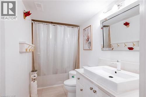 Modern bathroom featuring a rectangular vessel sink with a white single-handle faucet, a white vanity with paneling and brass hardware, and a framed mirror with integrated lighting - 171 Mcnichol Drive, Cambridge, ON 
