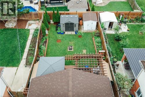 Expansive backyard featuring a central lawn, perimeter fencing, and a built-in fire pit - 171 Mcnichol Drive, Cambridge, ON 