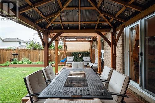 Expansive outdoor living area featuring a covered wooden pergola with a corrugated metal roof, string lighting, and a wood-finish deck - 171 Mcnichol Drive, Cambridge, ON 