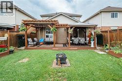 Spacious backyard featuring a wooden deck with a pergola, a separate gazebo, and a fire pit area - 