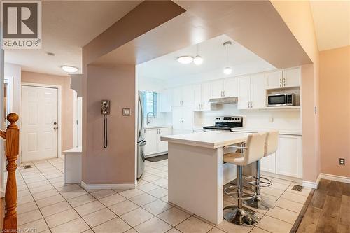Kitchen featuring white cabinetry, stainless steel appliances, a center island with a breakfast bar, pendant lighting, and tile flooring - 171 Mcnichol Drive, Cambridge, ON 