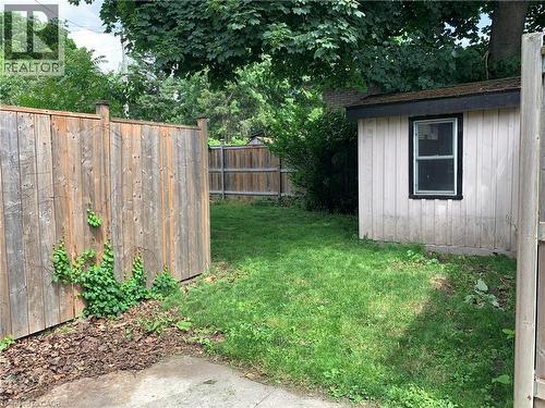 window, a wood fence, and mature trees in the background - 405 Macnab Street N, Hamilton, ON 