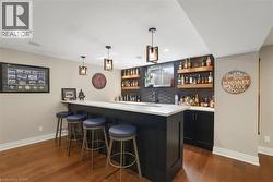 Custom wet bar featuring dark cabinetry, a white countertop, a textured dark backsplash, and open wood shelving - 